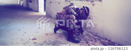 A professional soldier carries out a dangerous military mission in an abandoned building 116706123