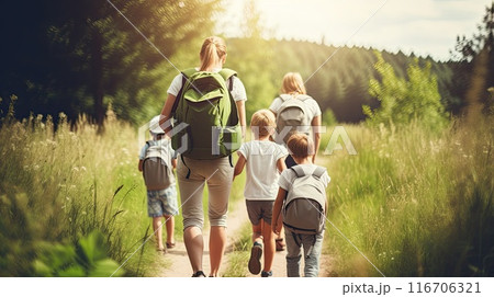 Parents and children walking hand in hand on a woodland trail. 116706321
