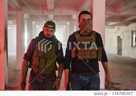 An abandoned building serves as the stronghold for a team of terrorists, fiercely guarding their occupied territory with guns and military equipment An abandoned building serves as the stronghold for a team of terrorists, fiercely guarding their occupied territory with guns and military equipment 116706387