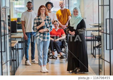 A diverse group of young business people congregates within a modern startup's glass-enclosed office, featuring inclusivity with a person in a wheelchair, an African American young man , and a hijab 116706455