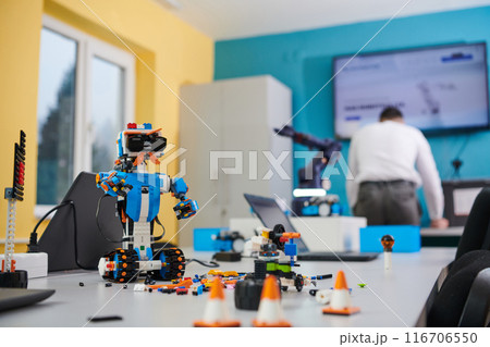 A student testing his new invention of a robotic arm in the laboratory, showcasing the culmination of his research and technological prowess. 116706550