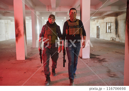 An abandoned building serves as the stronghold for a team of terrorists, fiercely guarding their occupied territory with guns and military equipment An abandoned building serves as the stronghold for a team of terrorists, fiercely guarding their occupied territory with guns and military equipment 116706698