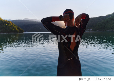Authentic triathlon athlete getting ready for swimming training on lake 116706728
