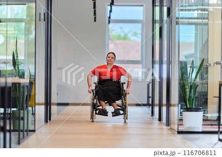 A modern young businesswoman in a wheelchair is surrounded by an inclusive workspace with glass-walled offices, embodying determination and innovation in the business world A modern young businesswoman in a wheelchair is surrounded by an inclusive workspace with glass-walled offices, embodying determination and innovation in the business world 116706811