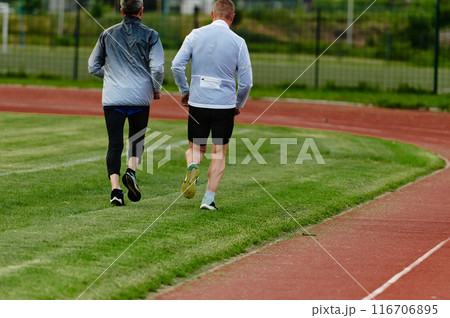 An inspiring and active elderly couple showcase their dedication to fitness as they running together on a lush green field, captured in a close-up shot of their legs in motion. An inspiring and active elderly couple showcase their dedication to fitness as they running together on a lush green field, captured in a close-up shot of their legs in motion. 116706895