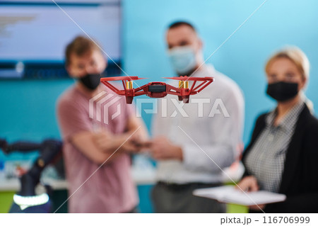 A group of students working together in a laboratory, dedicated to exploring the aerodynamic capabilities of a drone 116706999