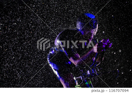 A triathlete braving the rain as he cycles through the night, preparing himself for the upcoming marathon A triathlete braving the rain as he cycles through the night, preparing himself for the upcoming marathon 116707094