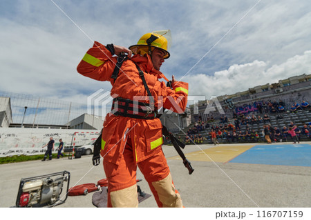 In a dynamic display of synchronized teamwork, firefighters hustle to carry, connect, and deploy firefighting hoses with precision, showcasing their intensive training and readiness for challenging 116707159