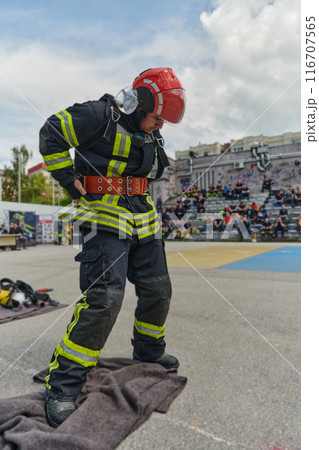 A firefighter dons the essential components of their professional gear, embodying resilience, commitment, and readiness as they gear up for a hazardous firefighting mission, a testament to their A firefighter dons the essential components of their professional gear, embodying resilience, commitment, and readiness as they gear up for a hazardous firefighting mission, a testament to their 116707565