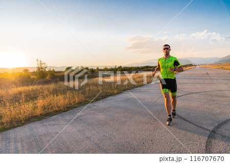 Triathlete in professional gear running early in the morning, preparing for a marathon, dedication to sport and readiness to take on the challenges of a marathon. Triathlete in professional gear running early in the morning, preparing for a marathon, dedication to sport and readiness to take on the challenges of a marathon. 116707670