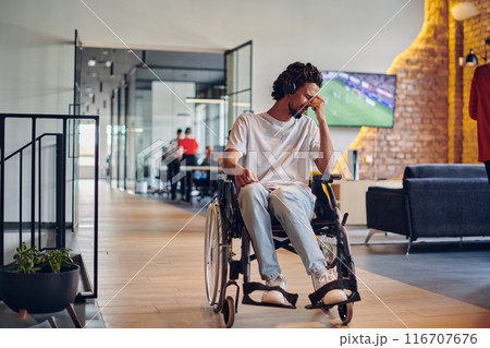 A sad businessman in a wheelchair occupies a hallway within a modern startup coworking center, embodying inclusivity and determination in the business environment A sad businessman in a wheelchair occupies a hallway within a modern startup coworking center, embodying inclusivity and determination in the business environment 116707676