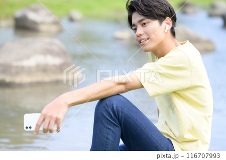 夏の水辺で涼みながらスマホを操作する男性 夏の水辺で涼みながらスマホを操作する男性 116707993