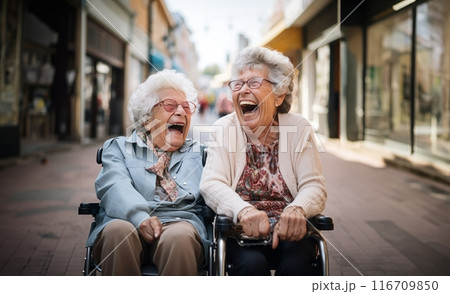 In a nursing home, two elderly women in wheelchairs find joy and companionship, embracing the comfort of their shared moments.Generated image 116709850