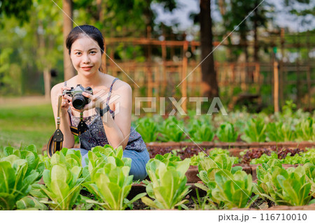happy asian women with camera in vegetable garden agriculture plant farm, eco green farming travel concept. 116710010