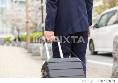 スーツケースを持って歩道を歩くビジネスマン 116711014