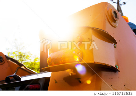 Close-up view of an excavator from behind with sun glare. Tail lights of a small excavator 116712632