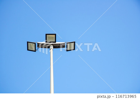 A street light stands tall against the backdrop of a clear blue sky A street light stands tall against the backdrop of a clear blue sky 116713965