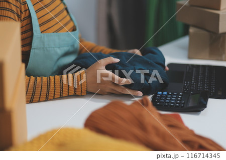 vlogger, blogger small SME business asian beautiful woman using mobile phone video call for sell clothes live stream selling online, show product present detail at home office, entrepreneur ecommerce 116714345