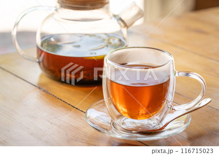 Warm Glass Teapot with Freshly Brewed Tea on Wooden Table - Cozy Beverage Moment Warm Glass Teapot with Freshly Brewed Tea on Wooden Table - Cozy Beverage Moment 116715023