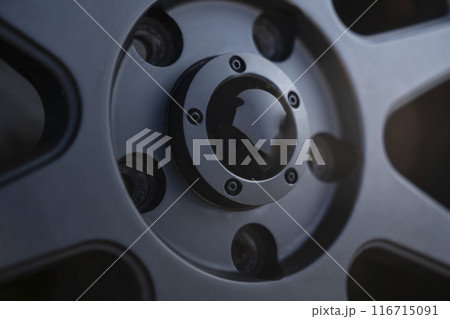 Closeup image of a modern car wheel, highlighting the intricate design of the center cap 116715091