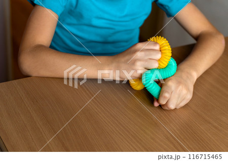 Multi colored anti-stress fidget push pop tube toys for children. Flexible corrugated pipe in kids hands. close-up. Caring for mental health 116715465