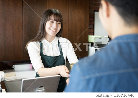 お客さんにコーヒーを渡すカフェの女性店員 お客さんにコーヒーを渡すカフェの女性店員 116716446