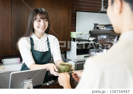 お客さんにコーヒーを渡すカフェの女性店員 お客さんにコーヒーを渡すカフェの女性店員 116716487