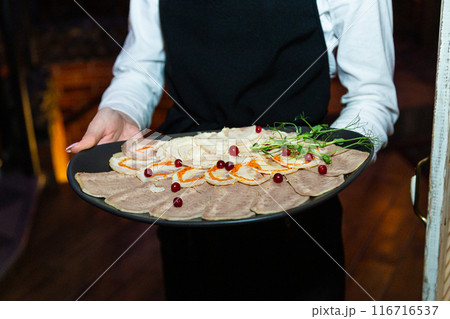 Meat cuts on a white plate in the hands of the 116716537