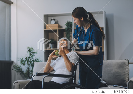 Asian physiotherapist helping elderly woman patient stretching arm during exercise correct with dumbbell in hand during training hand with patient Back problems in garden. Nursing home hospital 116716700