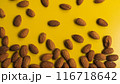Vibrant close-up of scattered almonds on a bright yellow background 116718642