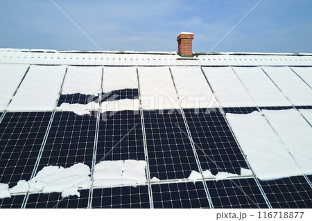 Aerial view of snow melting from covered solar photovoltaic panels installed on house rooftop for producing clean electrical energy. Low effectivity of renewable electricity in nothern region winter 116718877