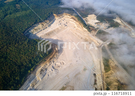 Aerial view of open pit mining of limestone materials for construction industry with excavators and dump trucks. 116718911