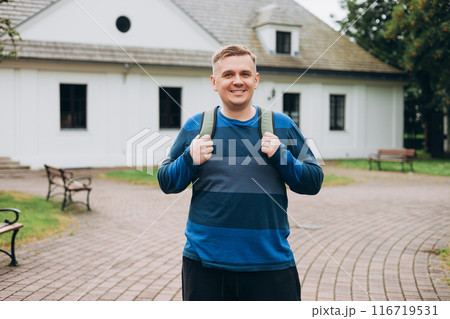 Smiling happy young man walking rest relax in green city park. 30s man smiling confident outdoors Smiling happy young man walking rest relax in green city park. 30s man smiling confident outdoors 116719531