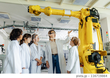Field trip to real robotics laboratory, encouraging children in career in robotics. Real scientist talking with young students, showing them robotic arm. 116719864