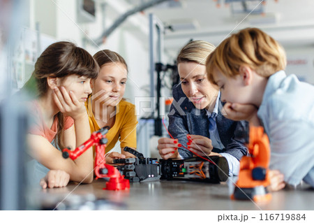 Children learning robotics in Elementary school. Young students building robot in after school robotics club. Field trip to real robotics laboratory. Children learning robotics in Elementary school. Young students building robot in after school robotics club. Field trip to real robotics laboratory. 116719884