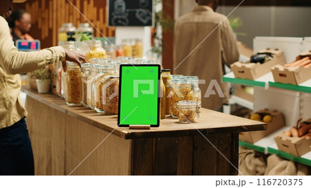 Greenscreen layout on tablet at local organic supermarket, ethically sourced products for sustainable lifestyle. Device running isolated mockup template or chromakey in zero waste eco store. Camera 1. 116720375
