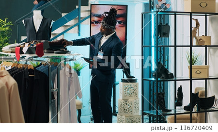 African american employee giving advice to senior customer in retail store, trying to find an elegant shirt on sale. Elderly client asking assistant for suggestions and recommendations. Camera A. 116720409