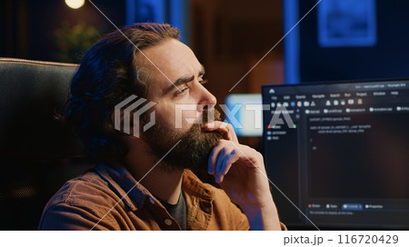 Software technician puzzled in front of computer screen while writing complex code, thinking of solution. IT expert feeling confused while trying to solve database bugs, camera A close up 116720429