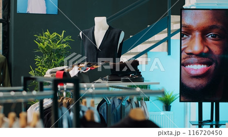 Shopping center having elegant shirts and suits on display, selling fashionable items and accessories. Empty clothing store at mall filled with formal or casual wear, consumerism concept. Camera A. Shopping center having elegant shirts and suits on display, selling fashionable items and accessories. Empty clothing store at mall filled with formal or casual wear, consumerism concept. Camera A. 116720450
