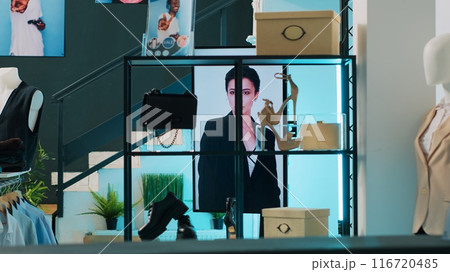 Empty trendy clothing store selling fashionable items and shoes, filled with new casual or formal merchandise. Shopping center boutique having fashion collection on racks, bags on display. Camera A. Empty trendy clothing store selling fashionable items and shoes, filled with new casual or formal merchandise. Shopping center boutique having fashion collection on racks, bags on display. Camera A. 116720485