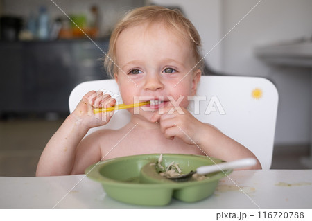Hungry little kid eating soup with noodles with big spoon 116720788