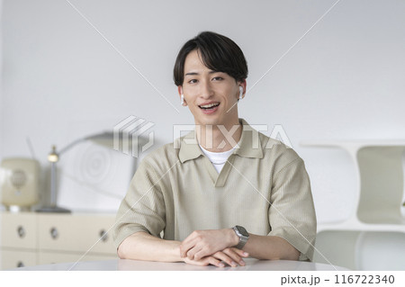 カメラ目線で話すイヤホンをした20代の男性 116722340