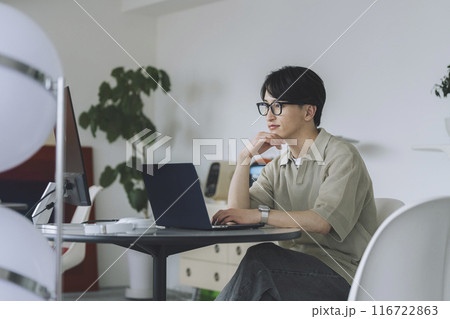 パソコンで作業をするメガネをかけた若い男性 パソコンで作業をするメガネをかけた若い男性 116722863