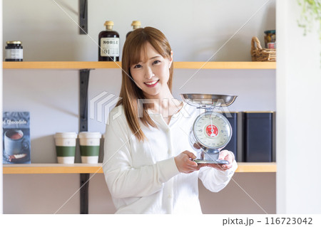 はかりを持って微笑む女性　　A smiling woman holding a scale 116723042
