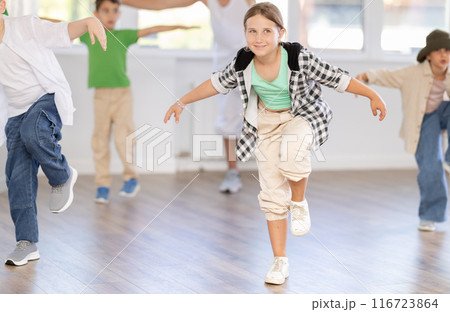 Young girl and group of positive children practicing energetic hip hop movements at dance school Young girl and group of positive children practicing energetic hip hop movements at dance school 116723864