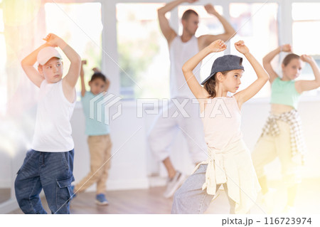 Preteen girl practicing hip hop choreography with peers and instructor Preteen girl practicing hip hop choreography with peers and instructor 116723974