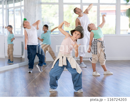 Group of teen children participating hip hop dance in class, following their teacher in dance school Group of teen children participating hip hop dance in class, following their teacher in dance school 116724203