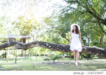 Happy Relax beautiful asian woman smiling face standing in green park outdoors garden. Young women enjoy nature morning Freedom Lifestyle. woman breathing fresh air and relax breath in green park Happy Relax beautiful asian woman smiling face standing in green park outdoors garden. Young women enjoy nature morning Freedom Lifestyle. woman breathing fresh air and relax breath in green park 116725847