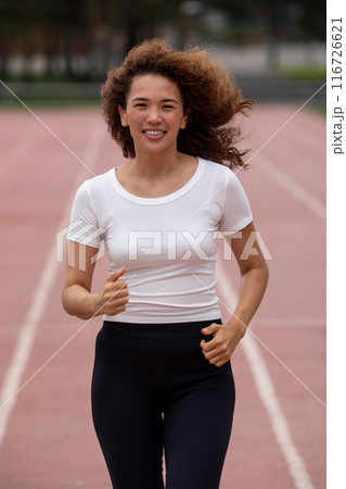Beautiful curly Asian woman running on the street 116726621