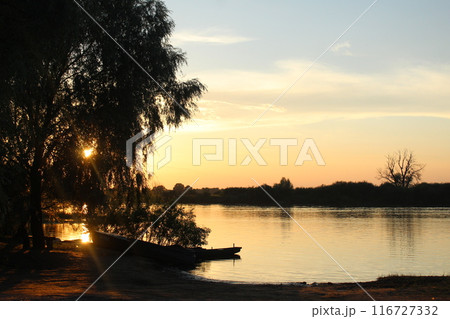 Sunrise over the river with black silhouettes of boat trees. Yellow Blue Black Evening Sunset Landscape 116727332
